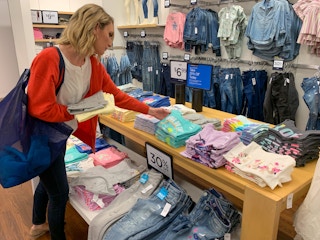 A woman looking at girls t-shirts inside Gap.