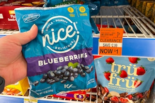 person holding a bag of frozen blueberries by a $1 clearance sign