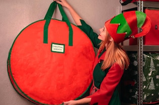 an elf hanging up a christmas wreath bag
