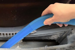 a hand cleaning a dryer vent with a blue hose