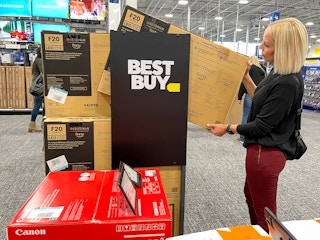 A woman in Best Buy looking at a TV.