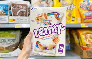 general mills cinnamon toast crunch remix snack mix box of 10 pouches being held by left hand in front of cereal snack shelves at walmart