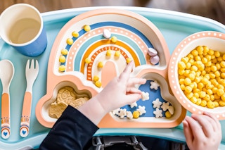 Lifestyle image of a rainbow Monbebe Mealtime Set being used to eat some snacks