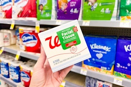 person holding a box of tissues in front of the shelves