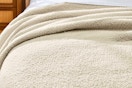Lifestyle image if the Better Homes & Gardens Cozy Knit Blanket over king sized bed