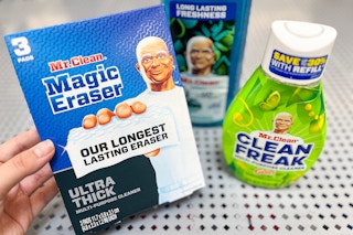 Hand holding a box of Mr Clean magic erasers in front of two other Mr Clean products
