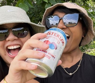 a person drinking a can of sparkling water next to another person