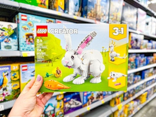 hand holding a Lego Creator Set for a white bunny, orange carrot, and yellow flower