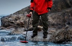 a person using a metal detector in a lake
