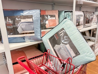 reversible comforters on a shelf and one in a shopping cart