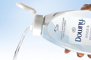 A hand pours a bottle of Downy Rinse & Refresh Free & Gentle