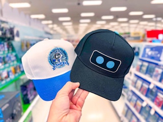 hand holding 2 playstation baseball caps in a target aisle