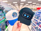 hand holding 2 playstation baseball caps in a target aisle