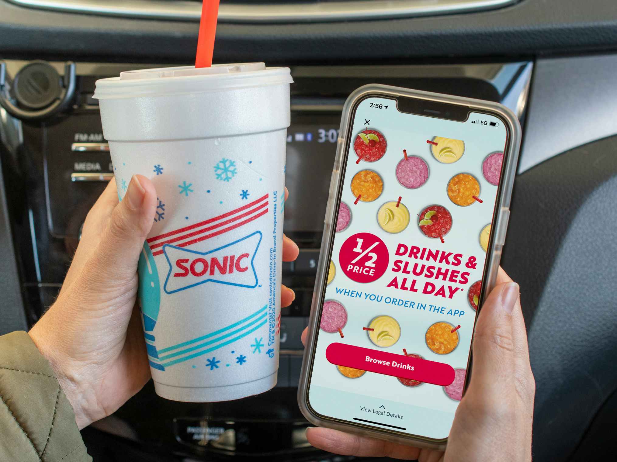 "1/2 drinks and slushes all day" ad inside the Sonic app on a cell phone, next to a sonic cup.