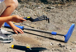 a blue metal detector on sand with a kid holding a mini rake