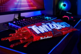 a bag of Twizzlers on a keyboard next to a computer
