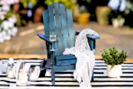 Lifestyle image of a navy wood Adirondack chair in an outdoor setting on a striped rug