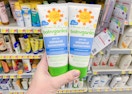 two bottles of babyganics sunscreen held in front of all sunscreens at walmart
