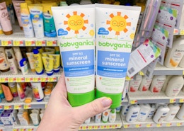 two bottles of babyganics sunscreen held in front of all sunscreens at walmart