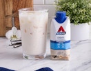 a protein shake next to a glass on a table 