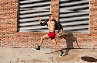A man posing on the sidewalk, while wearing Hanes apparel and socks.