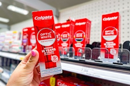 hand holding colgate optic white renewal toothpaste in front of a target shelf
