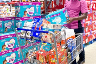 person in the diaper aisle at Sam's Club putting a box of Pampers diapers into a shopping cart