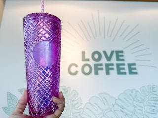 someone holding up their personal starbucks cup at starbucks