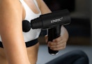 person using the mini massage gun on their arm