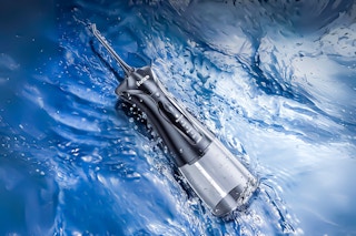 Lifestyle image of water flosser pick over flowing water
