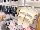 hand grabbing a pair of women's sandals sitting on a target shelf