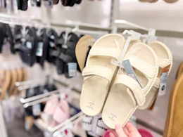 hand grabbing a pair of women's sandals sitting on a target shelf