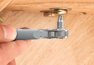 a screwdriver screwing in a screw in a wood panel