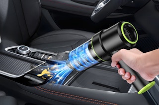a person using a handheld vacuum in a car