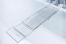 Lifestyle image of the Atomi Expandable Clear Acrylic Caddy Bathtub Tray over a bathtub