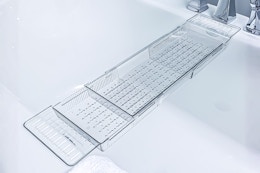 Lifestyle image of the Atomi Expandable Clear Acrylic Caddy Bathtub Tray over a bathtub