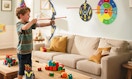 a kid in a living room playing with a bow and arrow set