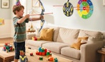 a kid in a living room playing with a bow and arrow set