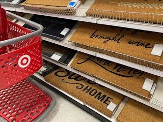 A target shopping cart parked up next to a shelf with a variety of doormats