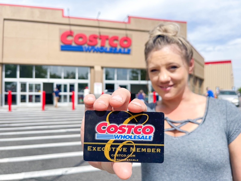 a woman holding a costco membership card in front of costco