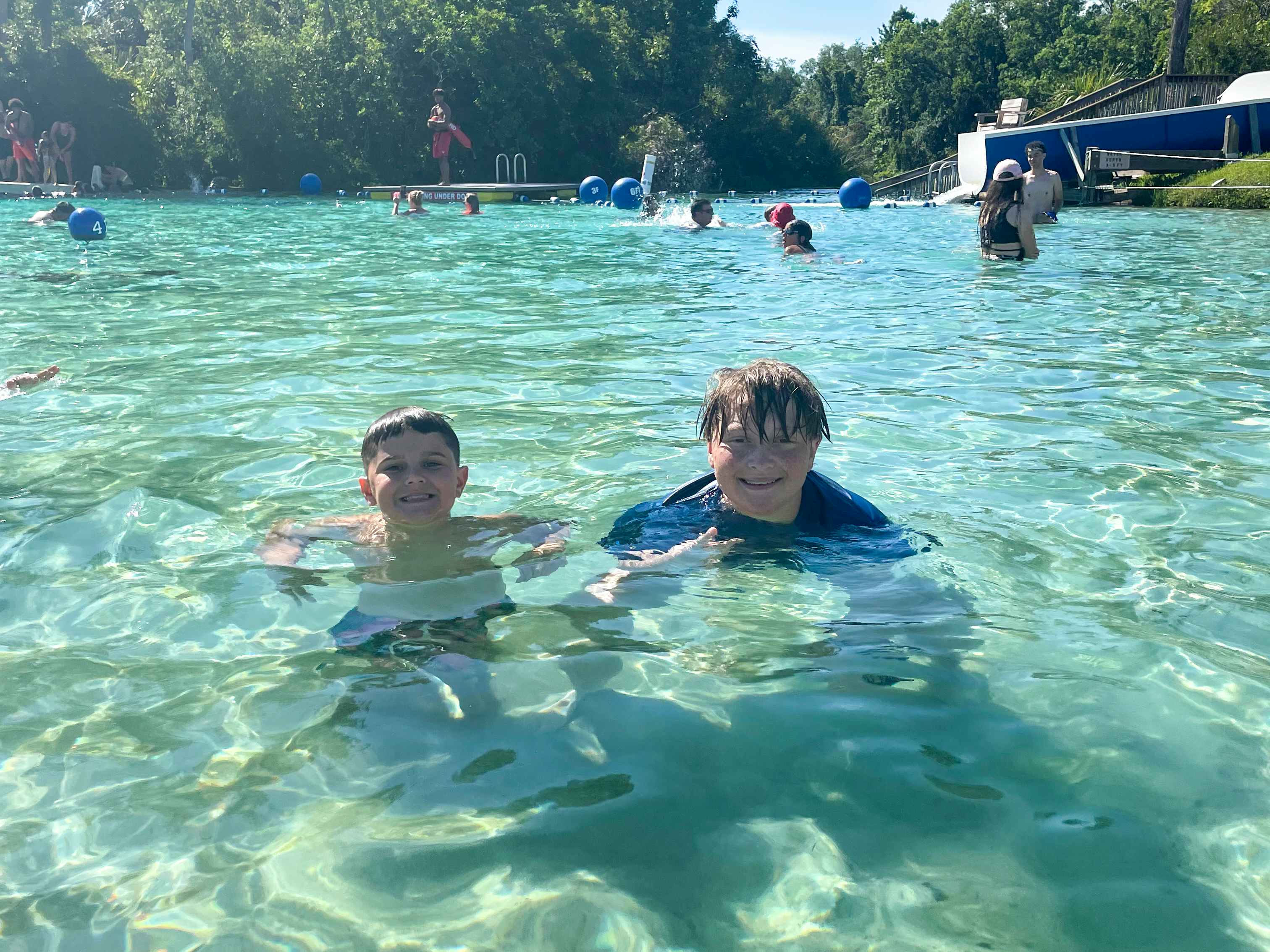 Two boys swimming in crystal blue water