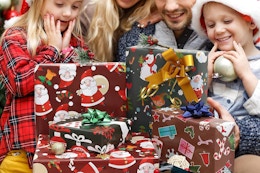 a family looking at christmas presents wrapped with christmas wrapping paper sheets