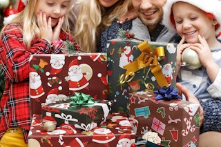 a family looking at christmas presents wrapped with christmas wrapping paper sheets