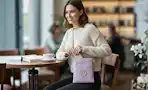 Women in a restaurant setting wearing a purple MK Collection purse