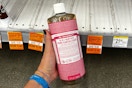 person holding a large bottle of dr bronners soap