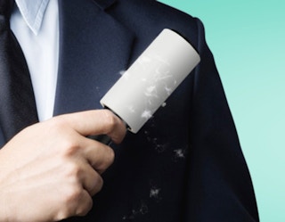 a person using a lint roller on their blazer