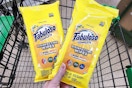 person holding 2 packs of fabuloso cleaning wipes over a cart