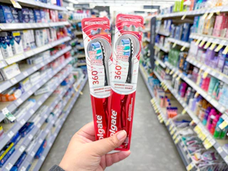 hand holding colgate toothbrushes in walgreens