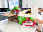 A hand holding up a paper towell roll in front of open Brawny packages