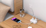 a nightstand with a powerstrip charging devices and glasses